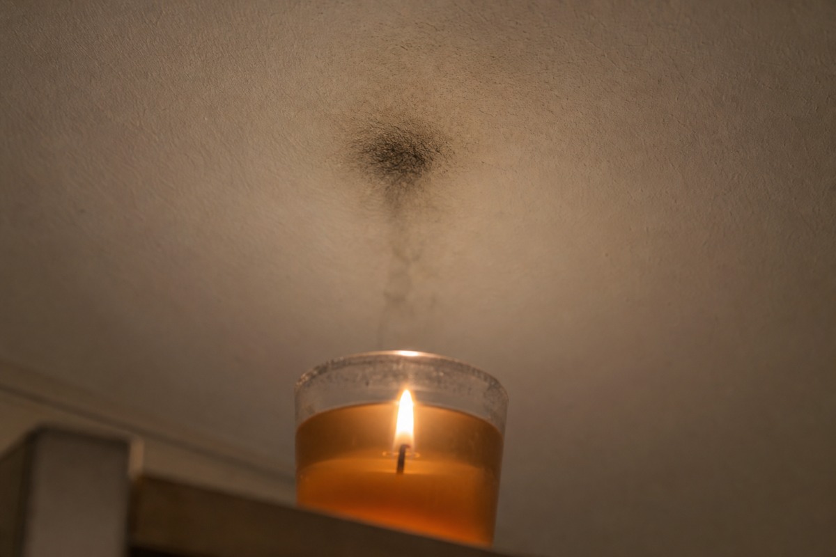 Trace de suie sombre sur un plafond blanc, juste au-dessus d'une bougie gel allumée dans un verre